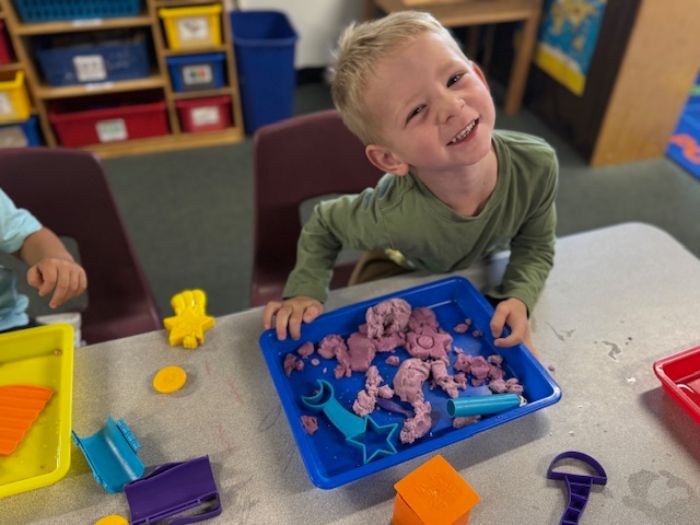 Kindergarten teacher teaching three kids to read